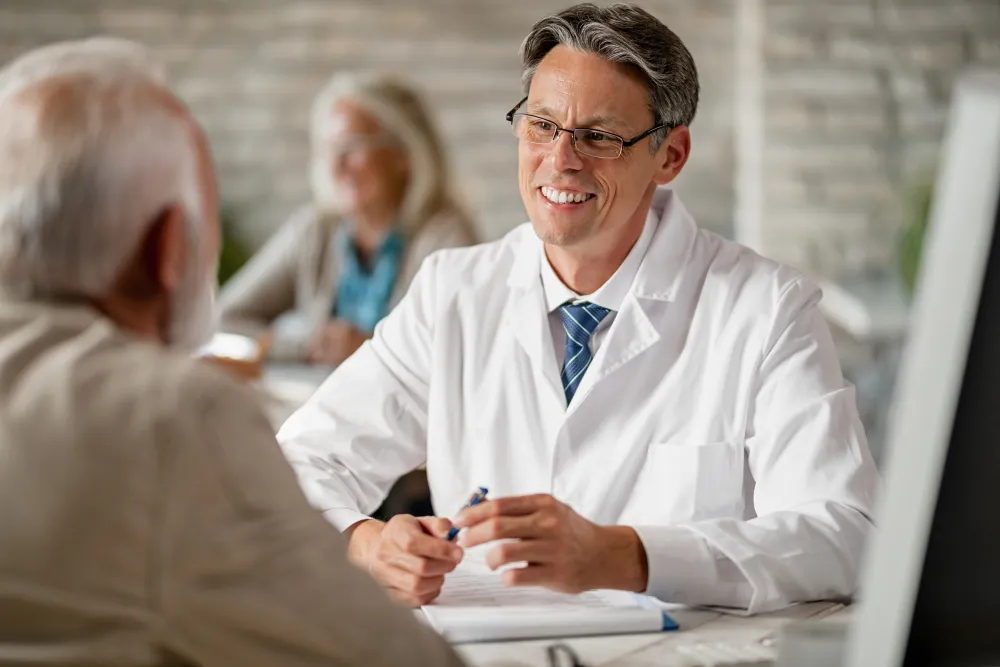 Arzt erklärt einer älteren Patientin Unterlagen in der Praxis